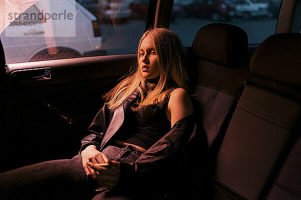 Blonde Frau sitzt abends in einem Autosalon