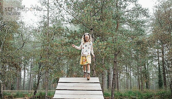 Mädchen geht im Herbst eine Holzrampe im Wald hinunter