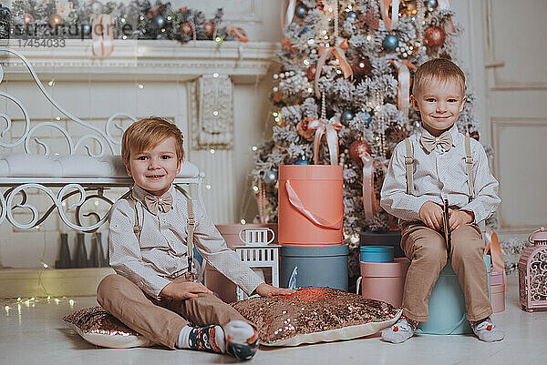 Fröhliche süße Kinderjungen  die Geschenke unter dem Weihnachtsbaum öffnen.