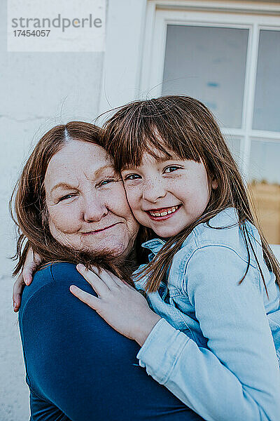 Nahaufnahme von Oma und Enkelin  die draußen lächeln und sich umarmen