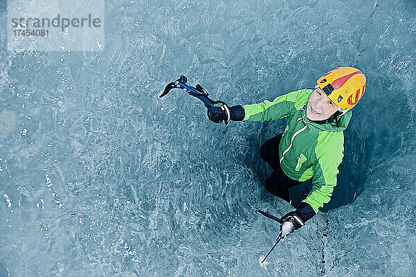 Frau klettert aus Gletscherspalte am Svinafellsjökull-Gletscher / Island