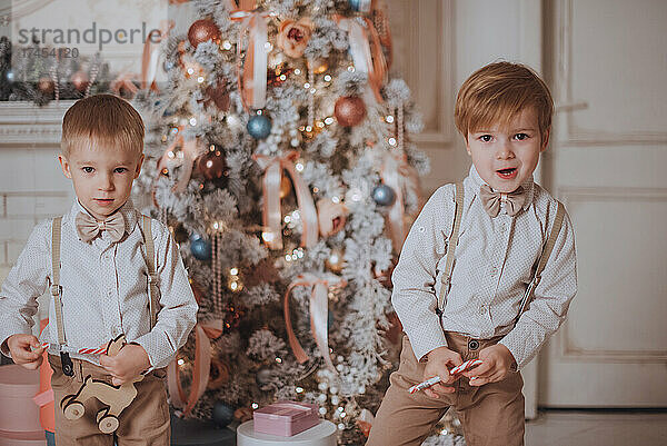 Fröhliche süße Kinderjungen  die Geschenke unter dem Weihnachtsbaum öffnen.