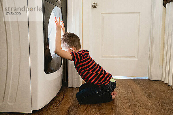 Verärgerter Junge vor der Waschmaschine