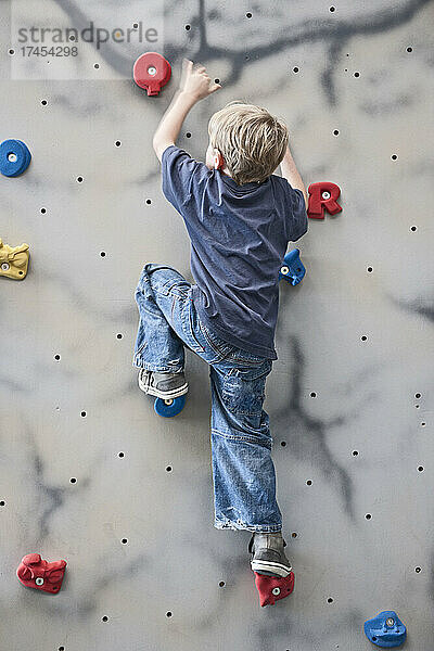 Junge klettert an einer Indoor-Boulderwand