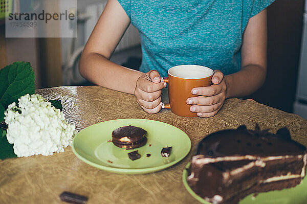 Teetrinken am Tisch mit Schokoladenkuchen in der Nähe weißer Hortensien