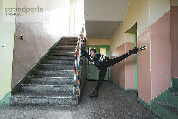 Athletische androgyne starke Tänzerin posiert an der Wand in der Pastellschule