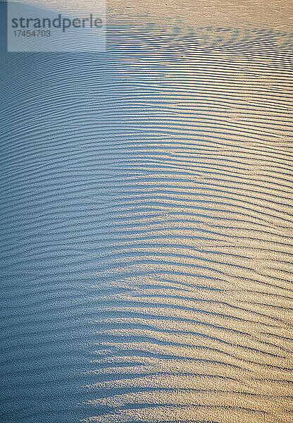 Licht und Muster auf Wellenformen an der weißen Sanddüne bei Sonnenuntergang