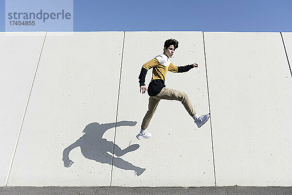 Junger Mann springt auf den Stadtmauerhintergrund