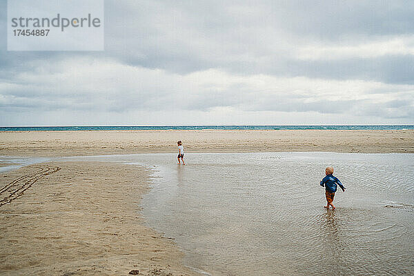 Junge läuft an einem bewölkten Tag spritzendes Wasser am Strand von Fuerteventura