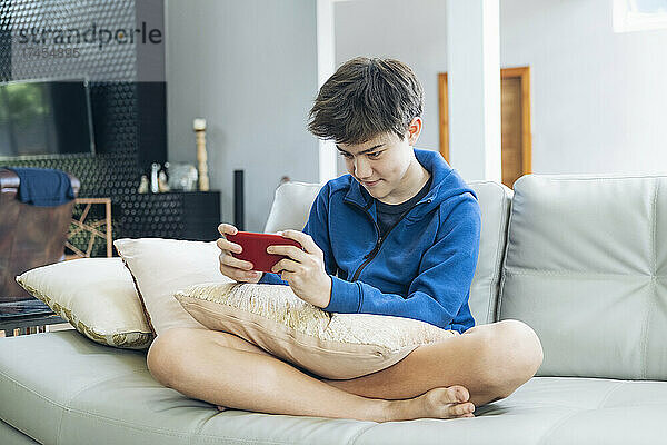 Der Junge spielt zu Hause ein Online-Spiel auf dem Smartphone