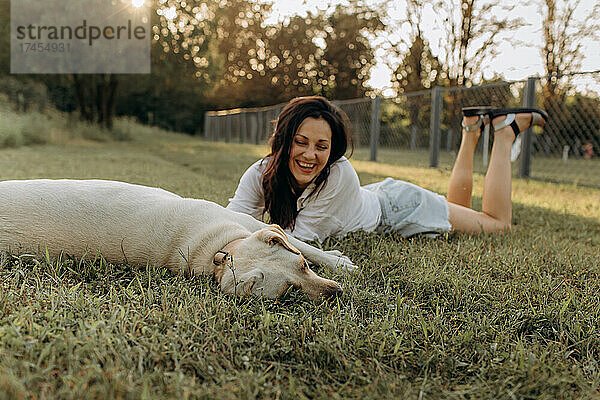Glückliche Frau umarmt und hat Spaß mit ihrem Labrador-Welpen im Freien.