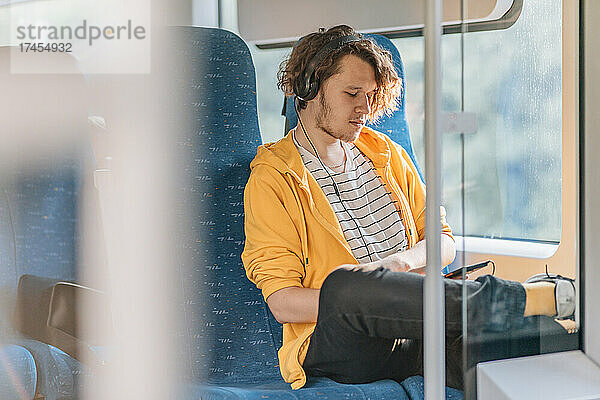 Junger Mann  Teenager  unterwegs im Zug mit Kopfhörern