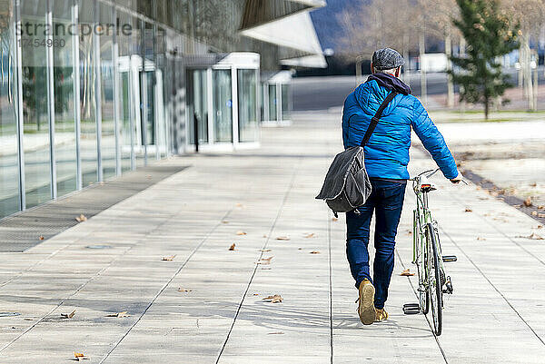 Älterer Mann fährt Fahrrad auf der Stadtstraße und hält eine Handtasche in der Hand