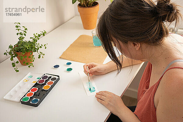 Frau malt mit Wasserfarben in ihrem Atelier zu Hause