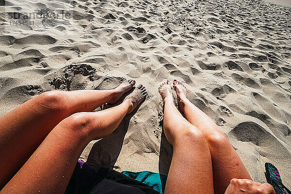 zwei Paar Frauenbeine im Sand am Strand