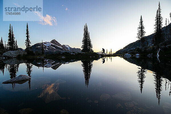 Silhouette eines Wanderers mit Spiegelung eines Alpensees bei Sonnenuntergang in Selkirks