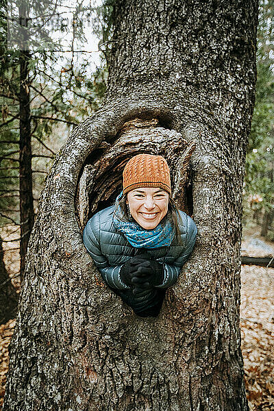 Frau mit Hut lächelt und lacht in einem großen Baumknoten