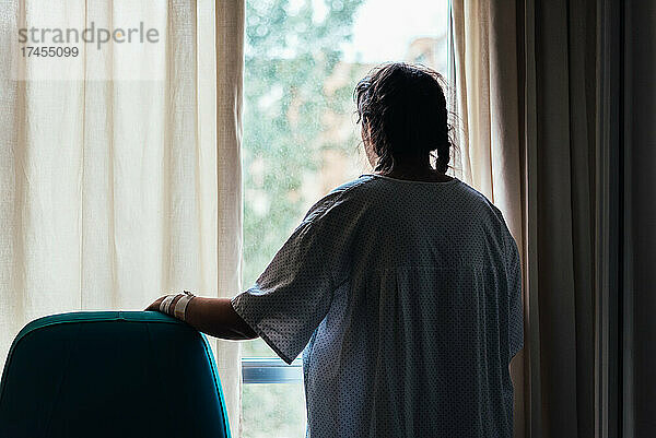 Junger Patient schaut aus einem Krankenhausfenster.
