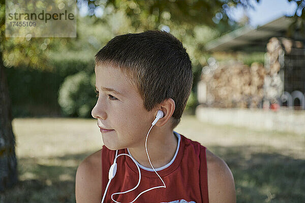 Ein süßer Junge hört Musik  während er wegschaut