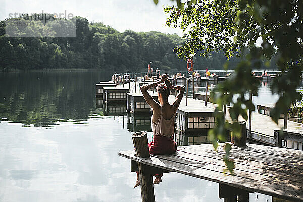 Person sitzt auf einem Holzsteg mit Blick auf den wunderschönen See in Polen