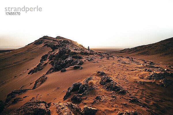 Junge Frau wandert in den Sonnenaufgang in der marokkanischen Wüste
