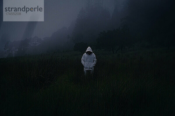 Ein geheimnisvoller Mann mit weißem Kapuzenpullover im dunklen  nebligen Wald