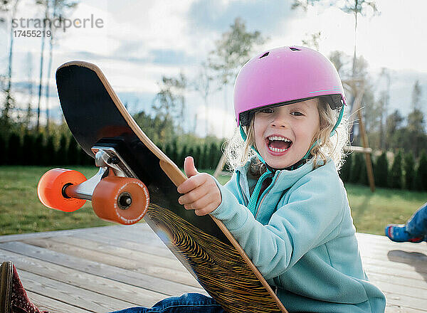 Porträt eines Mädchens  das auf einem Skateboard lacht  während es zu Hause spielt