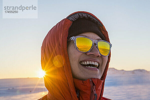 Porträt einer Frau  die vor dem arktischen Sonnenaufgang lacht