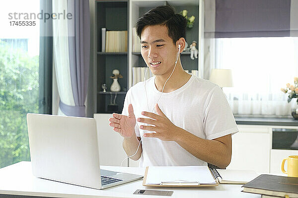 Junger Mann  der zu Hause online arbeitet und lernt.