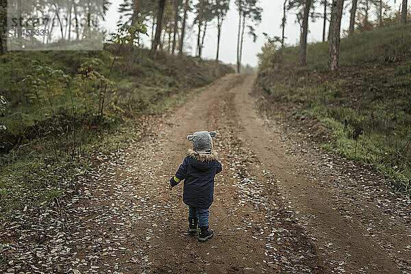 Kleinkind mitten im Wald auf einem Wanderweg bei nebligem Wetter