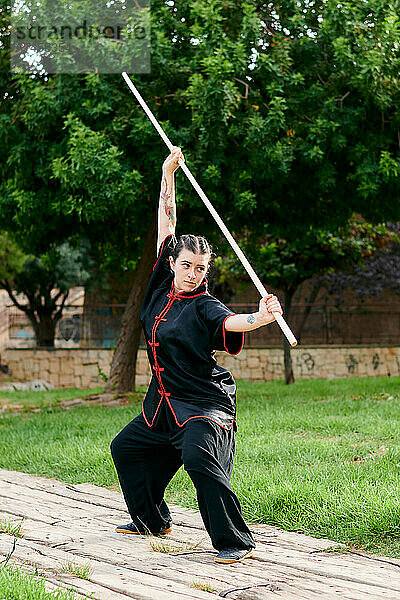 Frau in Uniform übt Kampfkunst mit einem Stock