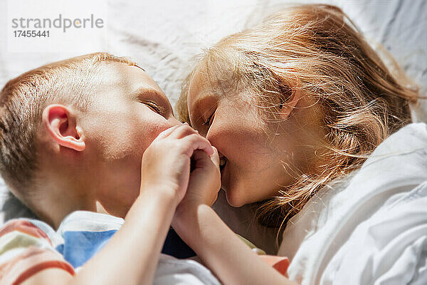 Kinder in der Morgensonne im Bett