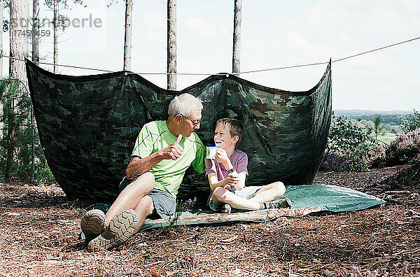 Opa und Enkel bauen gemeinsam im Wald ein Abenteuer