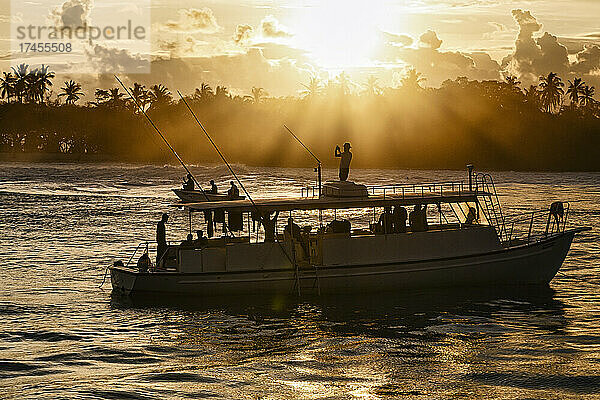 Boot mit naher tropischer Insel bei Sonnenuntergang