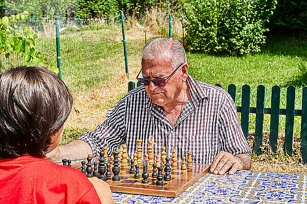 Großvater und Enkel spielen Schach im Garten