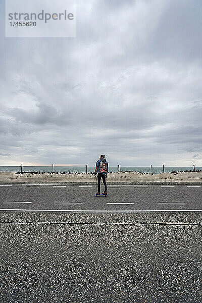 Ein Mann mit langen Haaren  der auf einer leeren Straße in Europa Schlittschuh läuft
