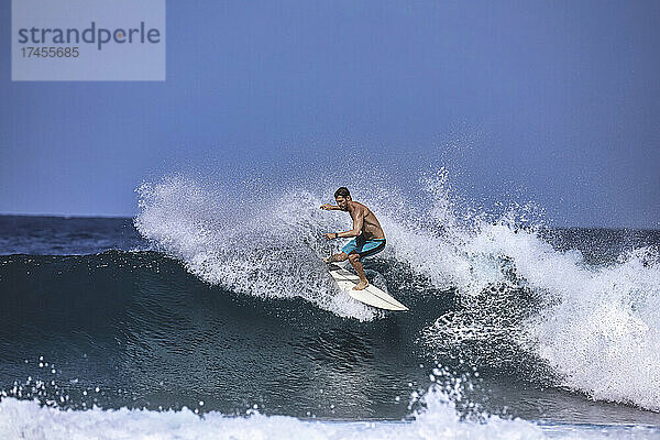 Surfer auf einer blauen Welle an einem sonnigen Tag