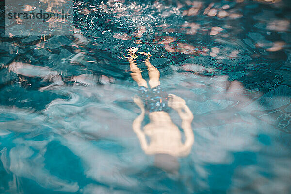 8 Jahre alter gesichtsloser Junge schwimmt in einem Pool