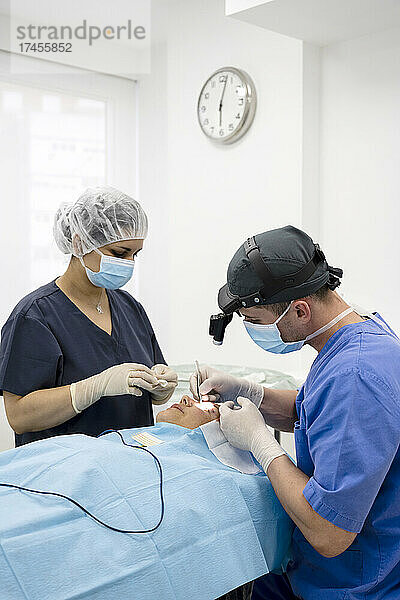 Der Chirurg näht das Augenlid nach einer plastischen Operation