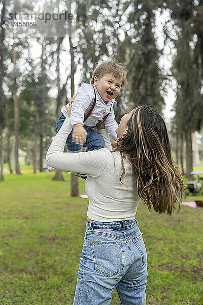 Mutter zieht ihr Kind groß  während es draußen glücklich lacht