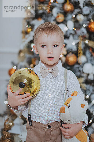 Fröhlicher  geschnittener Junge  der Geschenke unter dem Weihnachtsbaum öffnet.