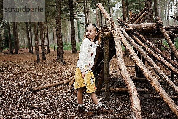 Mädchen stand im Herbst neben einem Holzhaus im Wald