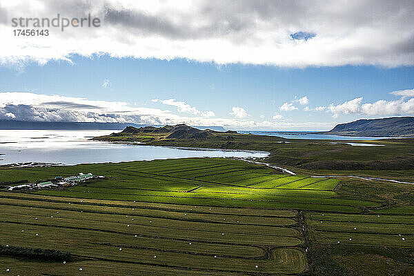 Die Sonne scheint auf eine Wiese auf einem Ackerland im Westen Islands.