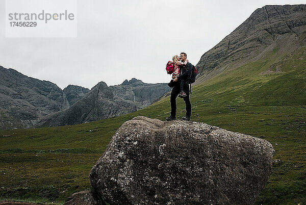 Vater umarmt seine Tochter  nachdem er in Schottland einen riesigen Felsbrocken bestiegen hat