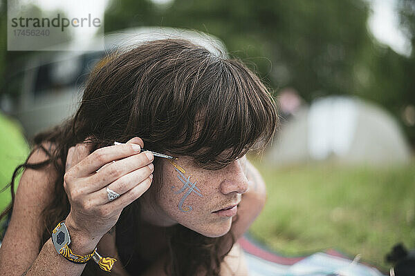 Natürliche Frau mit Sommersprossen bemalt Gesicht beim Camp-Picknick-Festival