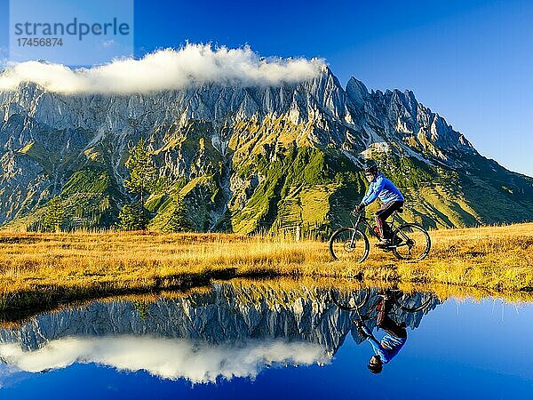 Mountainbiker vor Bergkulisse spiegelt sich in einem Bergsee  Mandlwand  Mandlwände  Hochkönig  Berchtesgadener Alpen  Mühlbach am Hochkönig  Pongau  Salzburg  Österreich  Europa