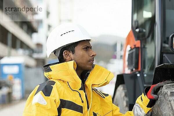 Junger Techniker mit Helm und gelber Schutzjacke außen arbeitend  Freiburg  Baden-Württemberg  Deutschland  Europa