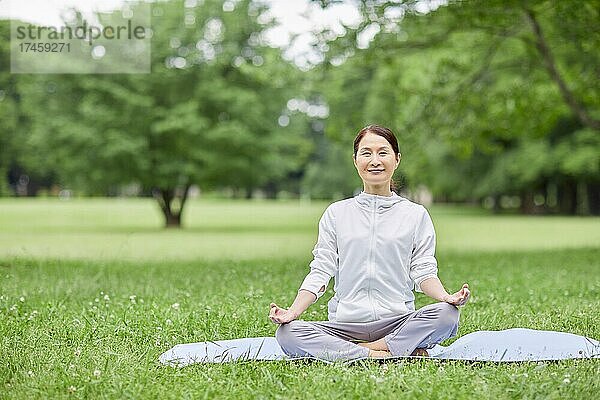 Eine japanische Seniorin trainiert in einem Stadtpark