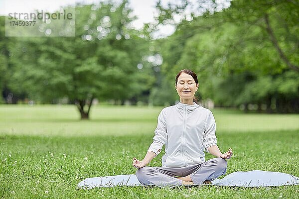 Eine japanische Seniorin trainiert in einem Stadtpark