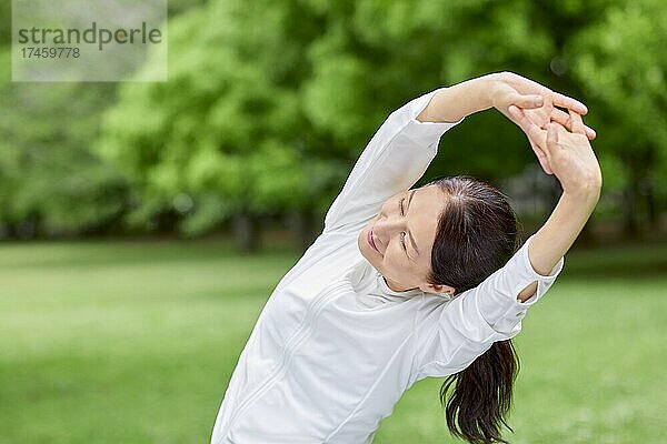 Eine japanische Seniorin trainiert in einem Stadtpark